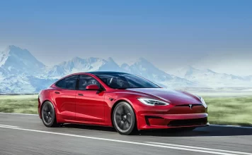 A red Tesla Model S Plaid driving past a mountain range