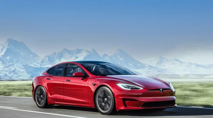 A red Tesla Model S Plaid driving past a mountain range