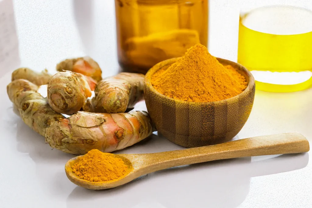 A wooden bowl and spoon containing pure turmeric curcumin powder