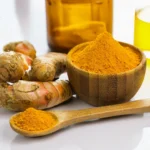 A wooden bowl and spoon containing pure turmeric curcumin powder