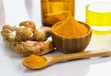 A wooden bowl and spoon containing pure turmeric curcumin powder