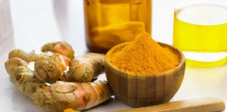 A wooden bowl and spoon containing pure turmeric curcumin powder