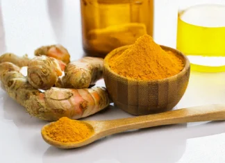 A wooden bowl and spoon containing pure turmeric curcumin powder