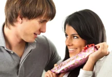 A man handing a gift to his girlfriend, who looks delighted while secretly hoping it's not socks!